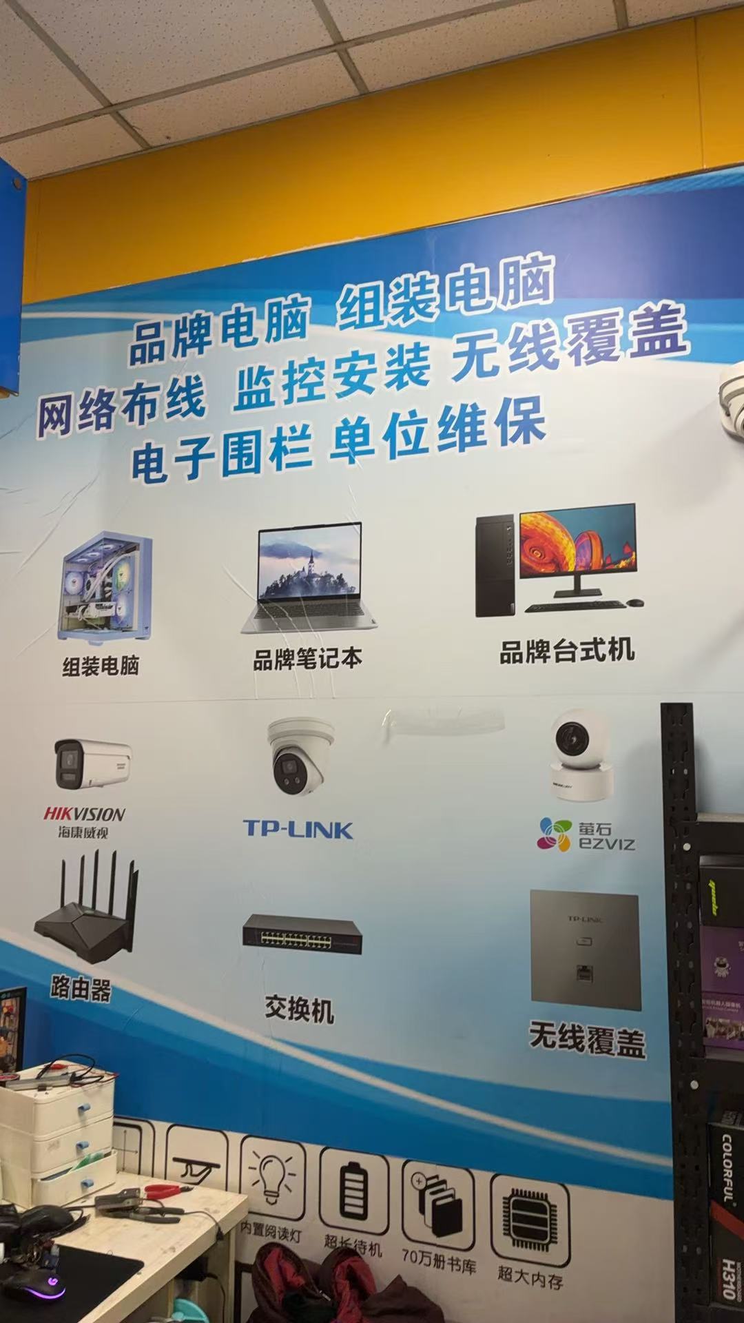 无锡青之松门店正面视角 - 百脑汇4E15摊位，玻璃柜台陈列电脑配件与外设，墙面悬挂蓝底白字「网络监控 青之松」吊旗招牌，周边可见 MSI 微星、技嘉品牌专柜